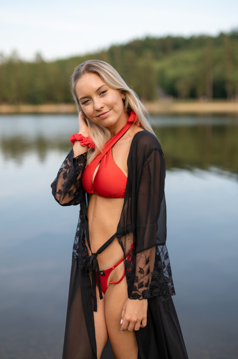 Červené bikini a na nich plážový přehoz černé barvy